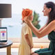 Mother puts sun hat on daughter as smartphone displays high uv alert practical response to sun