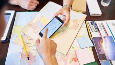 Close-up image of friends checking map on smartphone when planning road trip to the sea