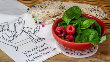 A bowl of raspberries and basil leaves