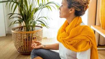 Portrait of authentic serene lady at home sitting on the floor in relaxation position with crossed legs smiling happy Mental healthy body care workout daily routine female people living alone