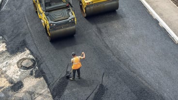 Workers lay a new asphalt coating using hot bitumen Work of heavy machinery and paver Top view