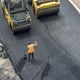 Workers lay a new asphalt coating using hot bitumen Work of heavy machinery and paver Top view