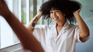 Beauty hair and mirror with a black woman in the bathroom of her home for a morning haircare routine Growth wellness and keratin with an attractive young female styling her afro in the house