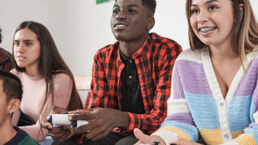 Multiracial young people playing video games at home - Generation z friends enjoy technology