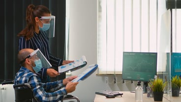 Business people wearing protective mask in new normal office making strategy, businessman sitting in wheelchair Team working in profesional workspace in corporate company during covid-19 pandemic.