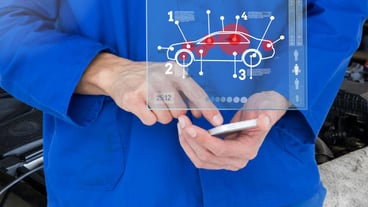 Mechanic using smartphone in garage with car mechanic interface