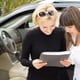 Blond woman smiling as she reads a contract for the purchase of her new car