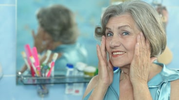 Senior woman in a bathroom with cream