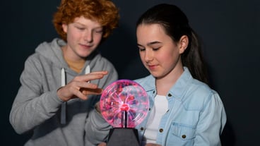 Medium-length children interacting with a plasma ball