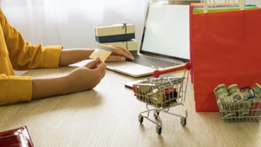 Woman uses credit card and laptop to shop online at home