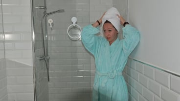 Woman wearing bathrobe and towel drying hair in bathroom