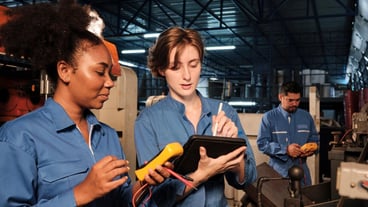 Two professional female engineers inspect machines electric systems at factory
