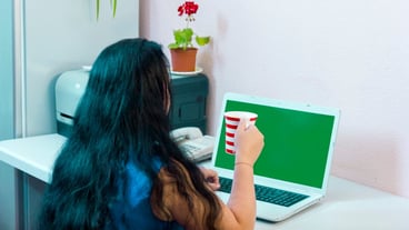 woman in a home office works for a laptop and drinks coffee