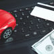 Credit card, dollar and red toy car on laptop keyboard.