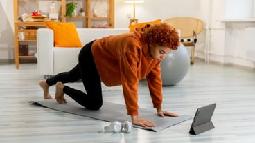 Fitness training session with a healthy, fit African girl doing sports exercises on a yoga mat on the floor.