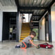 Side view of boy kid playing on the floor with car toy red color house stairs behind