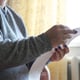 A woman in a warm sweater sits at home in front of the battery and holds a gas bill in her hands Energy crisis concept Horizontal photo
