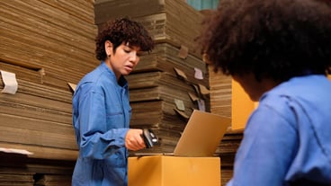 Two workers use a bar code scanner to check orders stock at parcels warehouse
