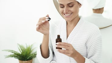 Beautiful girl with vitiligo smiles with a snow-white smile with moisturizing serum. Close up from a pipette from a pipette on the background of the hands.