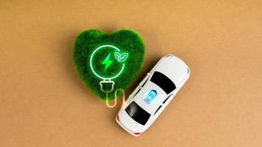 Electric battery charging vehicle with sustainable development concept Top view white toy car with charging battery icon power energy energy energy in green grass heart on recycled paper background
