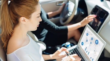 Involved in work. Serious smart intelligent businesswoman sitting in the car and typing on the keyboard while working on her project