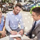 Car business, sales and people concept - happy couple with a dealership buying a car and signing documents at a car show or in a hall on a snow effect
