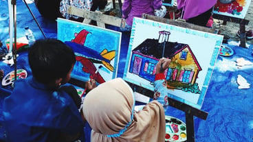 Rear view of boy and girl painting outdoors