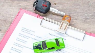 Green toy car and key on wooden desk
