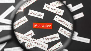 Magnifier glass over the red inscription motivation cut out of paper,