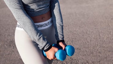 Unrecognizable athlete working out with dumbbells
