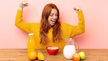 Teenager redhead girl having breakfast in a table celebrating a victory