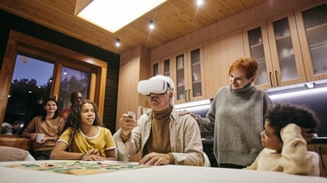 Mature woman and her two interracial grandchildren looking at senior man in vr headset