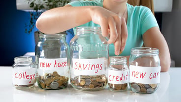 Young woman filling glass jars with money savings. Concept of financial investment, economy growth and bank savings.
