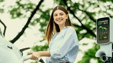Young woman recharging battery for electric car during road trip travel EV car in natural forest or national park Eco friendly travel during vacation and holiday Exalt