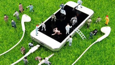 Mini toy workers working on their smartphones on the lawn