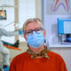 Portrait of retired patient in dental office looking on camera wearing face mask sitting on chair in waiting room clinic while doctor working. Concept of new normal dentist visit in coronavirus outbre
