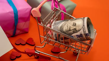 Beautiful packaged gifts with discounts lie near a shopping cart in which dollars on a beautiful orange background and hearts. Black friday concept. Discount concept
