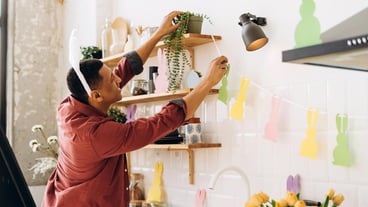 Latin smiling Man decorating kitchen for Easter hanging bunny garland