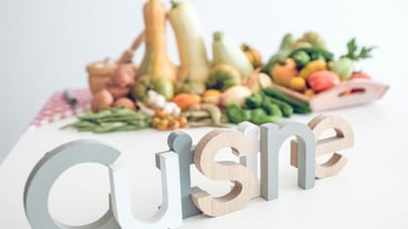 Composition of word cuisine against pile of assorted fresh ripe vegetables on white table including tomatoes and pumpkins with pepper