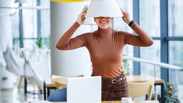 Girl in a cafe stands at a wooden table smiling and fooling around with coffee and playing with a lamp