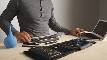 Unrecognizable man searches for guides on the internet while repairing his smartphone, replacing screen and battery