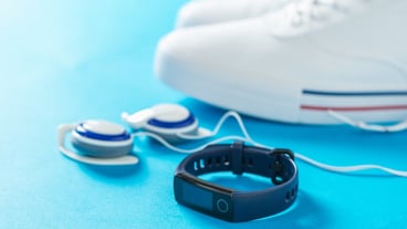 Blue chic bracelet, over-ear headphones and white sneakers on blue.