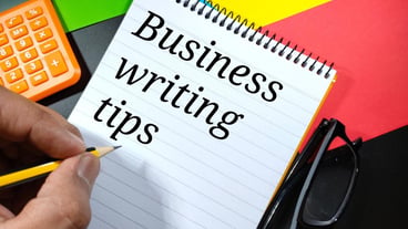 Word BUSINESS WRITTING TIPS on notebook with hand holding pencilBusiness concept