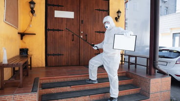 Coronavirus Pandemic A disinfector in a protective suit and mask sprays disinfectants in house