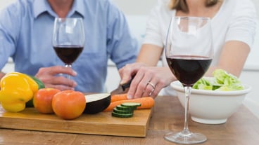Mid section of couple with wine glasses and vegetables