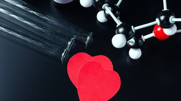 Two red paper hearts and molecular structure model on a black. Love chemistry concept