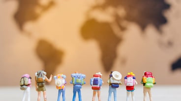 Miniature human travelers walking on the world map