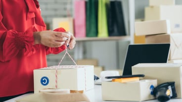 Online seller works at home office and packs shipping delivery box to customer.