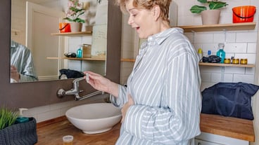 Woman holding pregnancy test confirming positive result in bathroom