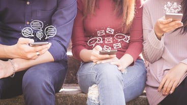 Midsection of women using mobile phones while sitting side by side